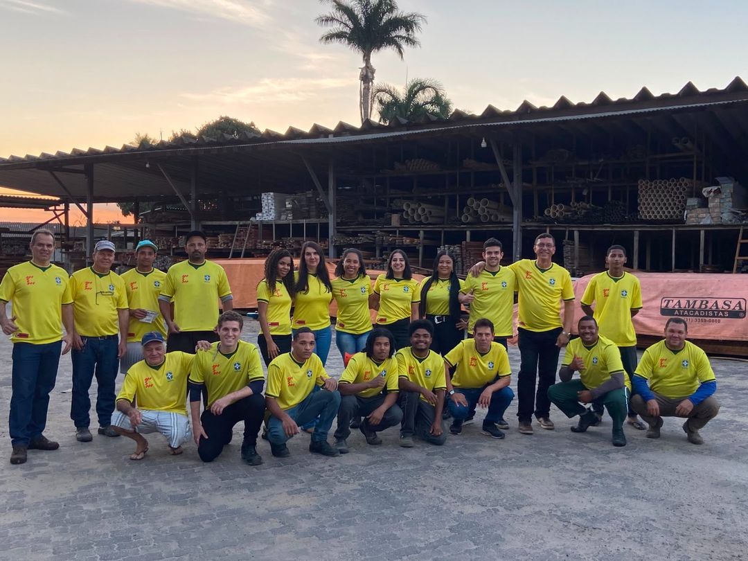 Equipe da Francischetto reunida no pátio da madeireira, ao entardecer, com o galpão de estoque de materiais ao fundo